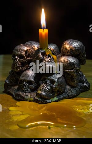 teschi con candela che brucia su sfondo di legno nel buio Foto Stock