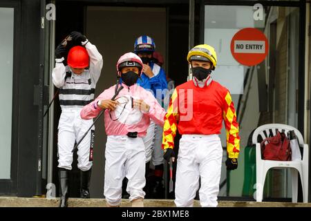 I jockey che indossano maschere facciali lasciano la sala di pesatura all'ippodromo di Newcastle. Foto Stock