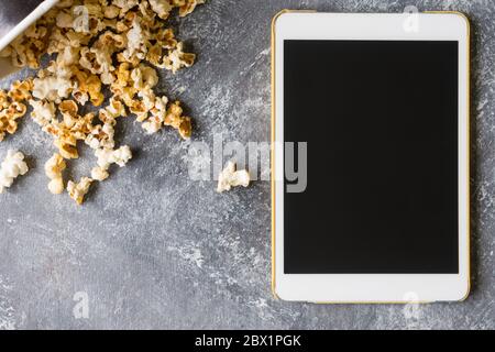 Tablet bianco touch computer gadget con popcorn su sfondo grunge. Foto Stock