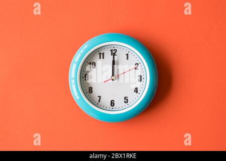 Orologio da parete blu su sfondo arancione, ore dodici Foto Stock