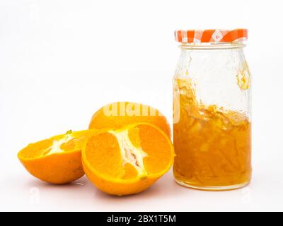 Arancio fresco con marmellata d'arancia in vaso di vetro su sfondo bianco. Foto Stock