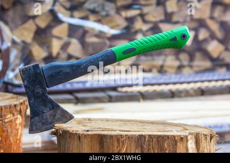 Un'ascia metallica si blocca in un moncone di legno dopo aver tritare il legno Foto Stock