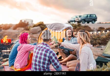 Amici felici tostare birre al barbecue campeggio festa - Gruppo giovani hipster persone divertirsi a mangiare e bere insieme in campeggio Foto Stock