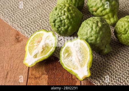 Primo piano di bergamotto o di lime kaffir su sfondo di tavola di legno. Foto Stock