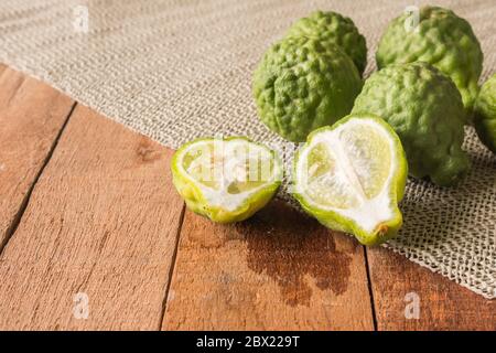 Primo piano di bergamotto o di lime kaffir su sfondo di tavola di legno. Foto Stock