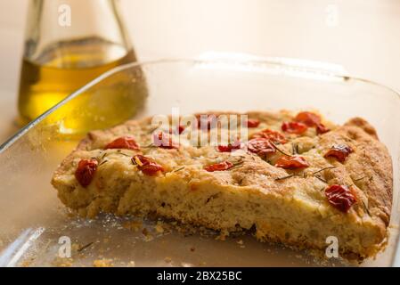 primo piano della focaccia genovese italiana, tradizionale cucina italiana con luce calda e naturale e olio d'oliva, e ciliegia di pomodoro e rosmarino in cima Foto Stock