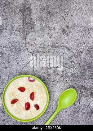 Sewai o kheer consumati in occasione di festival eid o indiani. Servito con condimenti di ciliegia rossa in una ciotola verde. Foto Stock