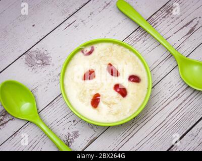Sewai o kheer consumati in occasione di festival eid o indiani. Servito con condimenti di ciliegia rossa in una ciotola verde. Foto Stock
