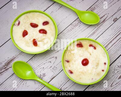 Sewai o kheer consumati in occasione di festival eid o indiani. Servito con condimenti di ciliegia rossa in una ciotola verde. Foto Stock