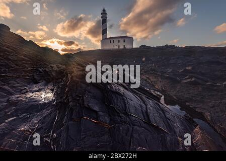 faro all'alba in una giornata invernale con cielo nuvoloso a Minorca, Spagna Foto Stock