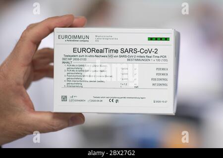 04 giugno 2020, Schleswig-Holstein, Lübeck: Un dipendente di Euroimmun detiene un 'EURO RealTime SARS-COV-2 Test' (testo tedesco), un cosiddetto test PCR, in un'anticamera di un laboratorio di Euroimmun, che può rilevare un'infezione in corso con il nuovo coronavirus. Il Presidente del Ministro Günther di Schleswig-Holstein si è recato giovedì in visita a Euroimmun e si è informato della produzione di test per la diagnosi della nuova malattia infettiva Covid-19. La società con sede a Lübeck attualmente fornisce fino a tre milioni di test anticorpali alla settimana in tutte le parti del mondo. Foto: Christian Charisius/dpa Foto Stock