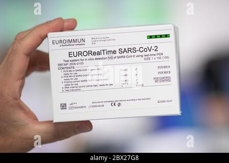 04 giugno 2020, Schleswig-Holstein, Lübeck: Un dipendente di Euroimmun detiene un 'EURO RealTime SARS-COV-2 Test' (testo tedesco), un cosiddetto test PCR, in un'anticamera di un laboratorio di Euroimmun, che può rilevare un'infezione in corso con il nuovo coronavirus. Il Presidente del Ministro Günther di Schleswig-Holstein si è recato giovedì in visita a Euroimmun e si è informato della produzione di test per la diagnosi della nuova malattia infettiva Covid-19. La società con sede a Lübeck attualmente fornisce fino a tre milioni di test anticorpali alla settimana in tutte le parti del mondo. Foto: Christian Charisius/dpa Foto Stock