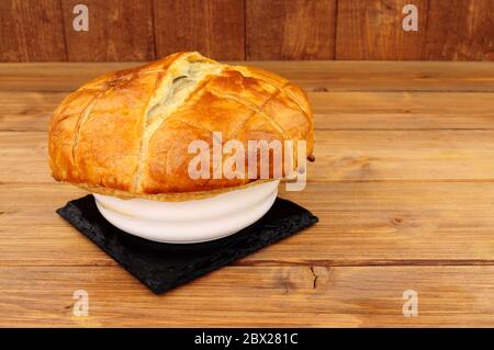 Bistecca e torta di ale individuali in un piatto di ceramica con pasta sfoglia su fondo di legno Foto Stock