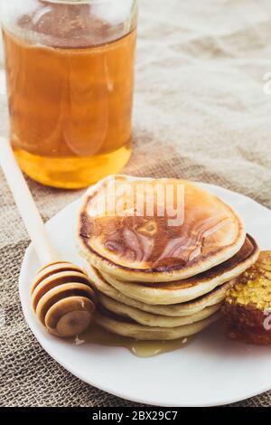 Frittelle dolci calde fresche - il miele spesso scorre da pancake a piatto - colazione rustica Foto Stock