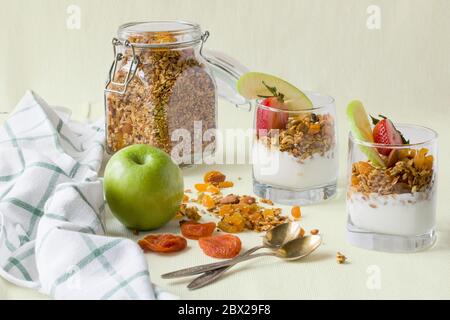 Due porzioni in tazze trasparenti di muesli fatti in casa con yogurt, noci e frutta secca Foto Stock