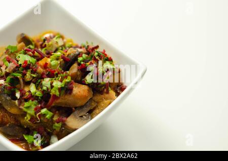 Un stufato di carne, patate, funghi e un mix di peperoni serviti in una ciotola bianca, pasto delizioso Foto Stock