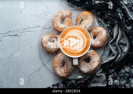 Caffè con latte art e piccola ciambella di vino con zucchero e cannella e ingredienti. Dessert di ciambelle Foto Stock