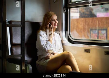 Una donna che usa uno smartphone su un treno Foto Stock