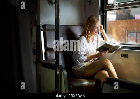 Una donna che legge un libro su un treno Foto Stock