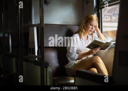 Una donna che legge un libro su un treno Foto Stock