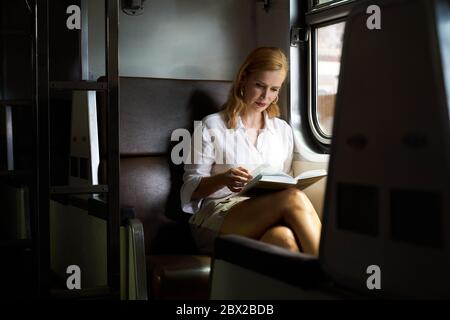 Una donna che legge un libro su un treno Foto Stock