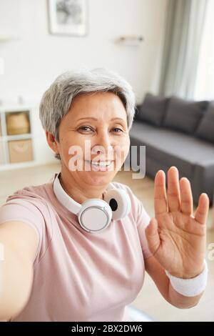 Ritratto di donna anziana sorridente alla macchina fotografica e sventolando la mano dice Ciao Foto Stock