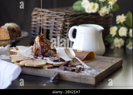 pezzo di brownie al cioccolato con caramello yummy su un pannello di legno scuro, pezzi di cioccolato rotto e un caraffa bianco del latte. Luce naturale Foto Stock