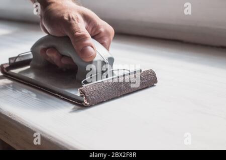 Preparazione della superficie per la verniciatura - smerigliatura manuale e rimozione del vecchio strato di vernice Foto Stock