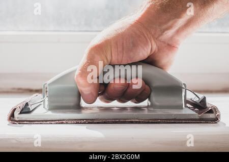 Livellare la superficie con carta vetrata - rimuovere la vernice vecchia e lo strato di sporco per strato Foto Stock