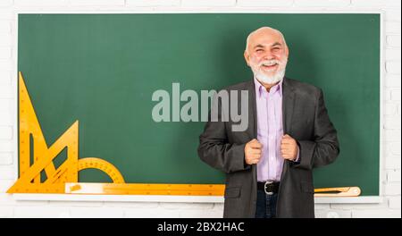 insegnante di uomo anziano usa gli attrezzi di matematica. l'uomo del docente bearded spiega la geometria sulla lavagna. torna a scuola. Strumenti grafici matematici. Lezione di trigonometria in classe. Scopri qui. Foto Stock