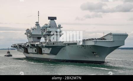 La Royal Navy Aircraft carrier HMS Queen Elizabeth (R08) ritornò a Portsmouth, Regno Unito il 4 giugno 2020 per imbarcarsi con il personale di 617 Squadron (i Dambuster) insieme alle loro attrezzature per sostenere un'ala aerea di F-35B Lightning II. La nave salpa e guiderà un gruppo di sciopero di portaerei in un esercizio chiamato Crimson Ocean. L'aeromobile F-35B e gli elicotteri che lo accompagnano probabilmente si uniranno alla nave una volta che sarà di nuovo in mare. Foto Stock