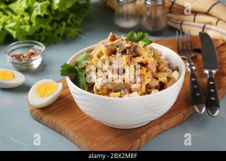 Insalata con prosciutto, uova, cipolla e funghi in una ciotola bianca su tavola di legno, formato orizzontale, Closeup Foto Stock