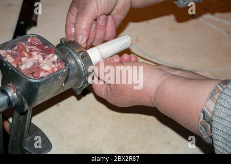 Produzione di salsiccia fatta in casa. Ripieno intestino di maiale con meat.The immagine mostra una donna che tira budello sul tubo di un macinacaffè di carne. è possibile visualizzare pa Foto Stock