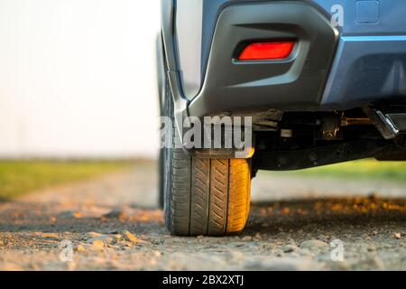 Primo piano della ruota blu fuoristrada su strada di ghiaia. Viaggiando in auto, avventura nella fauna selvatica, spedizione o viaggio estremo su un SUV auto. Offroa Foto Stock