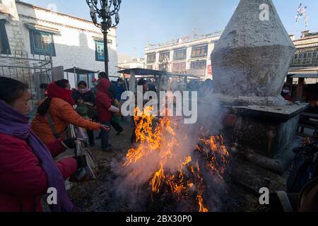 Cina, Tibet Regione autonoma, Lhasa, Barkhor o vecchio quartiere tibetano, pellegrini che mettono offerte nel fuoco, vicino al tempio di Jokhang, elencato come Patrimonio Mondiale dell'UNESCO Foto Stock