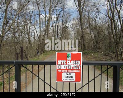 Donna su un marciapiede oltrepassa un cancello chiuso al sito storico Apple River Fort state di Elizabeth, Illinois, durante l'ordine di rifugio COVID-19 Foto Stock