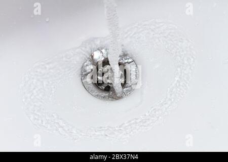 acqua che cade nel lavello a lento movimento, scarico closeup Foto Stock