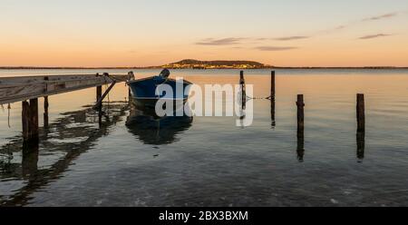 Una barca ormeggiata sull'Etang de Thau e in fondo a Mont-Saint-Clair (Sète), in Hérault, in Occitanie, nel sud della Francia Foto Stock