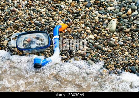 Snorkeling blu e maschera per immersioni sulla spiaggia di ciottoli Foto Stock