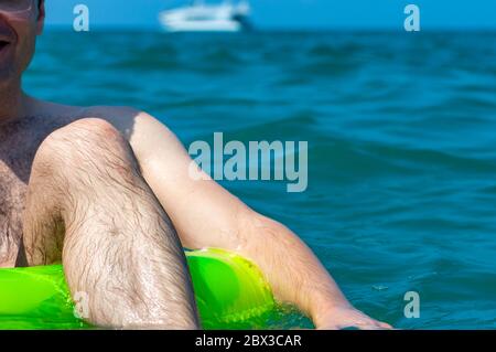 Uomo che nuota su un anello di gomma gonfiabile in mare. Foto Stock