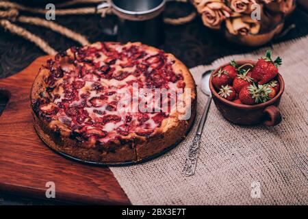 Torta wodden con torta di fragole fatta in casa su tavolo di pietra scura e sfondo nero. Foto Stock