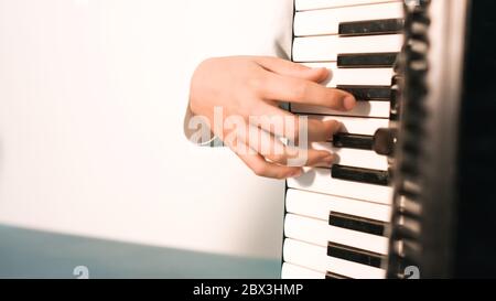 Giovane ragazzo che suona e pratica fisarmonica a piano. Foto Stock