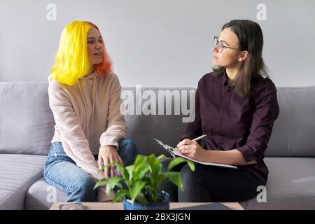 Ragazza teen che dà l'intervista al lavoratore sociale. Psicologo scolastico che parla con lo studente Foto Stock