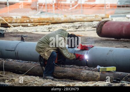 Riparazione di approvvigionamento idrico urbano o di condotte fognarie. L'operatore sta saldando il tubo. Foto Stock