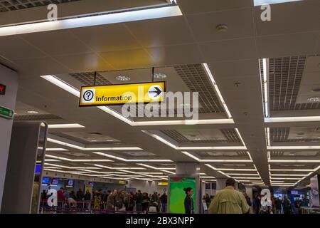 Piscina giallo luminoso segno di invito con un punto interrogativo e un cartello stradale su Airport e la stazione della metropolitana. Il passeggero in attesa sul punto di controllo Foto Stock