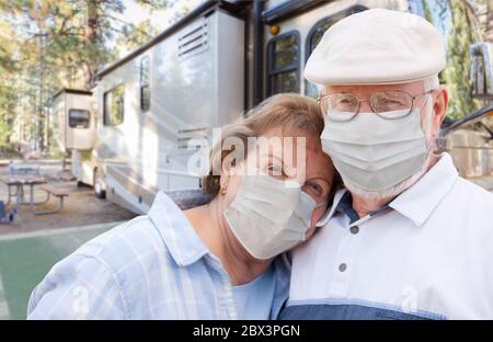 Coppia senior che indossa maschere mediche di fronte al loro bel RV al campeggio. Foto Stock