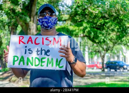 Un manifestante ondeggia un segno che denuncia il razzismo mentre si è protestato contro la brutalità della polizia, il 4 giugno 2020, al Memorial Park di Mobile, Alabama. Foto Stock