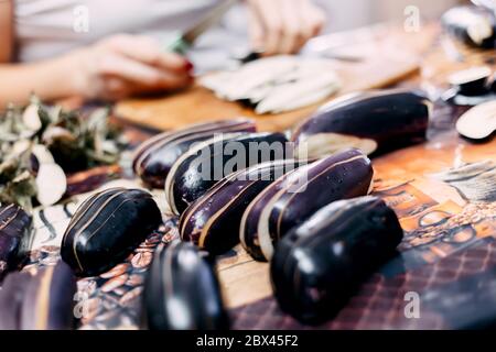 Il cuoco taglia le melanzane con un coltello Foto Stock