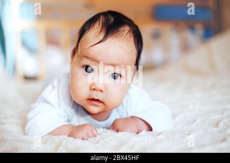 Baby girl sul suo stomaco. Ricerca con espressioni di sorpresa. Foto Stock