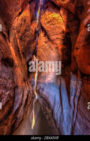 Una lunga esposizione di luce calda e morbida riflessa nella piscina nel colorato Tunnel slot Canyon nel Grand Staircase-Escalante National Monument nello Utah. Foto Stock